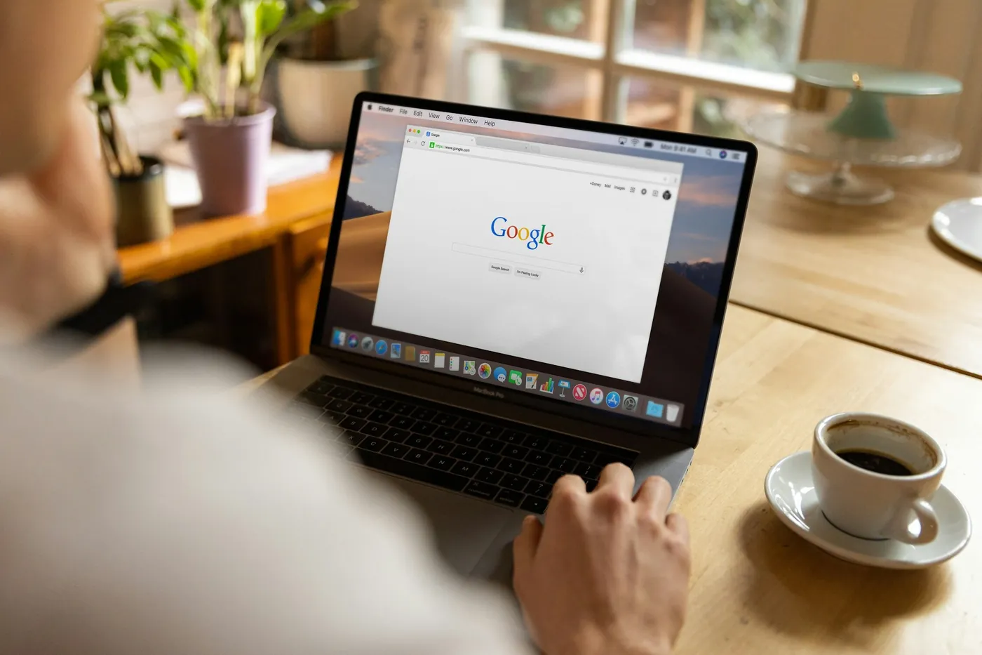 Laptop cu pagina de căutare Google deschisă, lângă o cafea